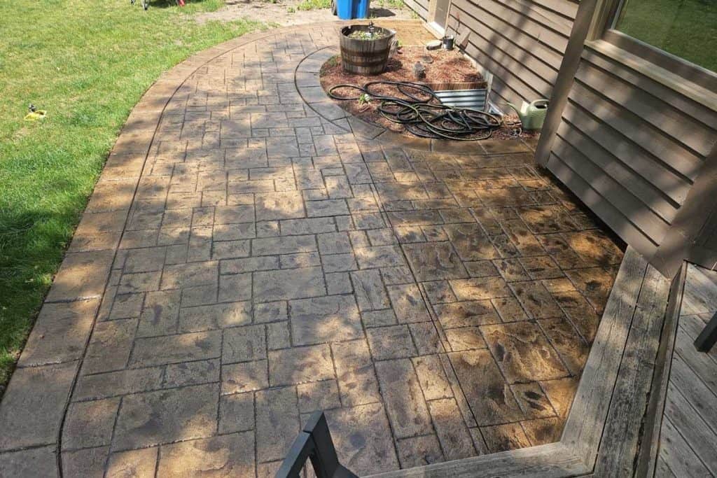 Stamped concrete patio walkway beside house and lawn