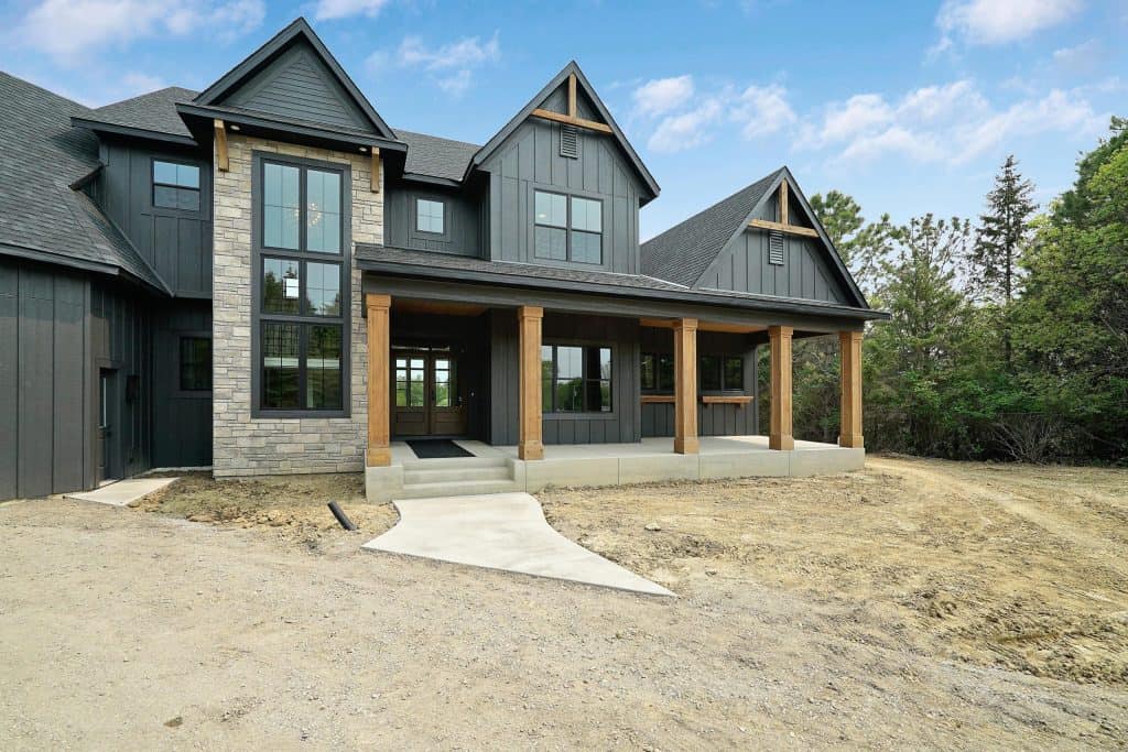 A modern residential house with a concrete porch and black exterior siding.
