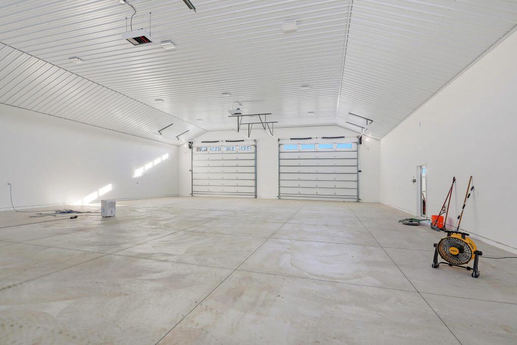 A spacious, clean concrete garage with white walls and ceiling, featuring two large garage doors.
