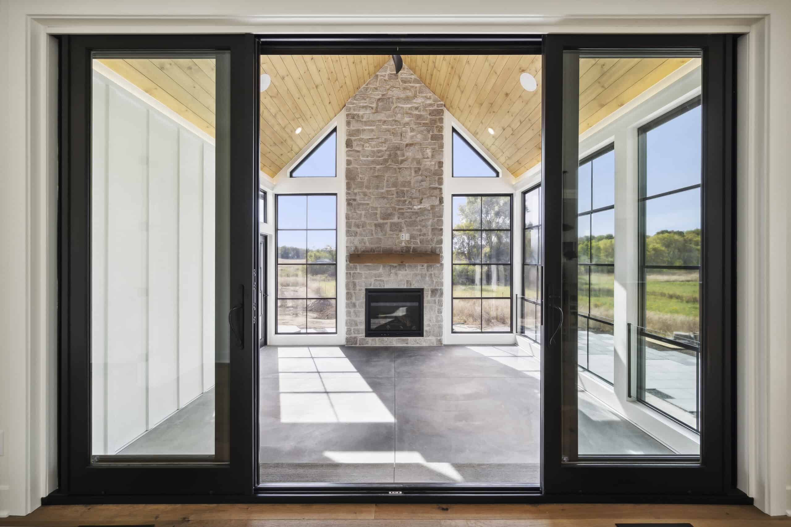 Modern sunroom with large glass sliding doors, vaulted ceiling, and fireplace, home improvement.