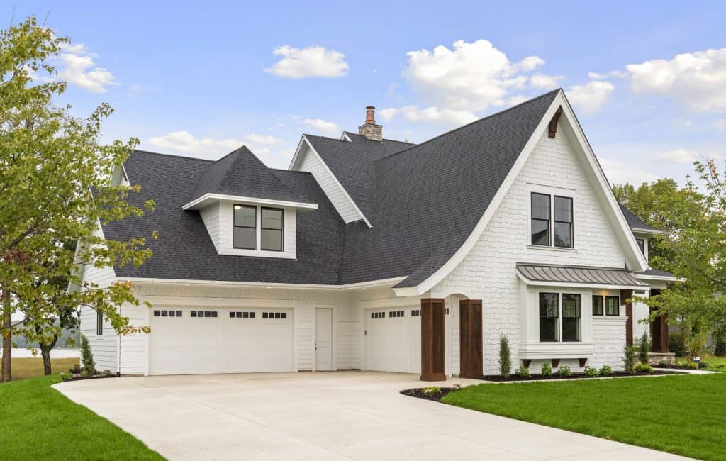 A modern white house with a custom concrete driveway and landscaped yard.