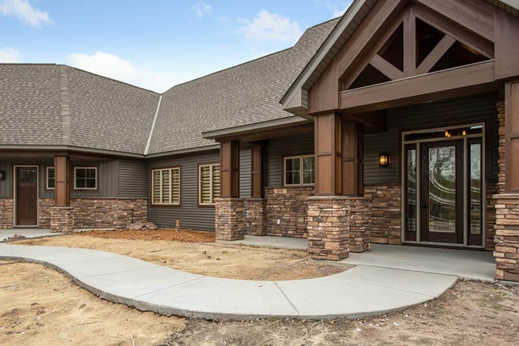 A modern residential concrete walkway with decorative stone accents and wooden architectural details.