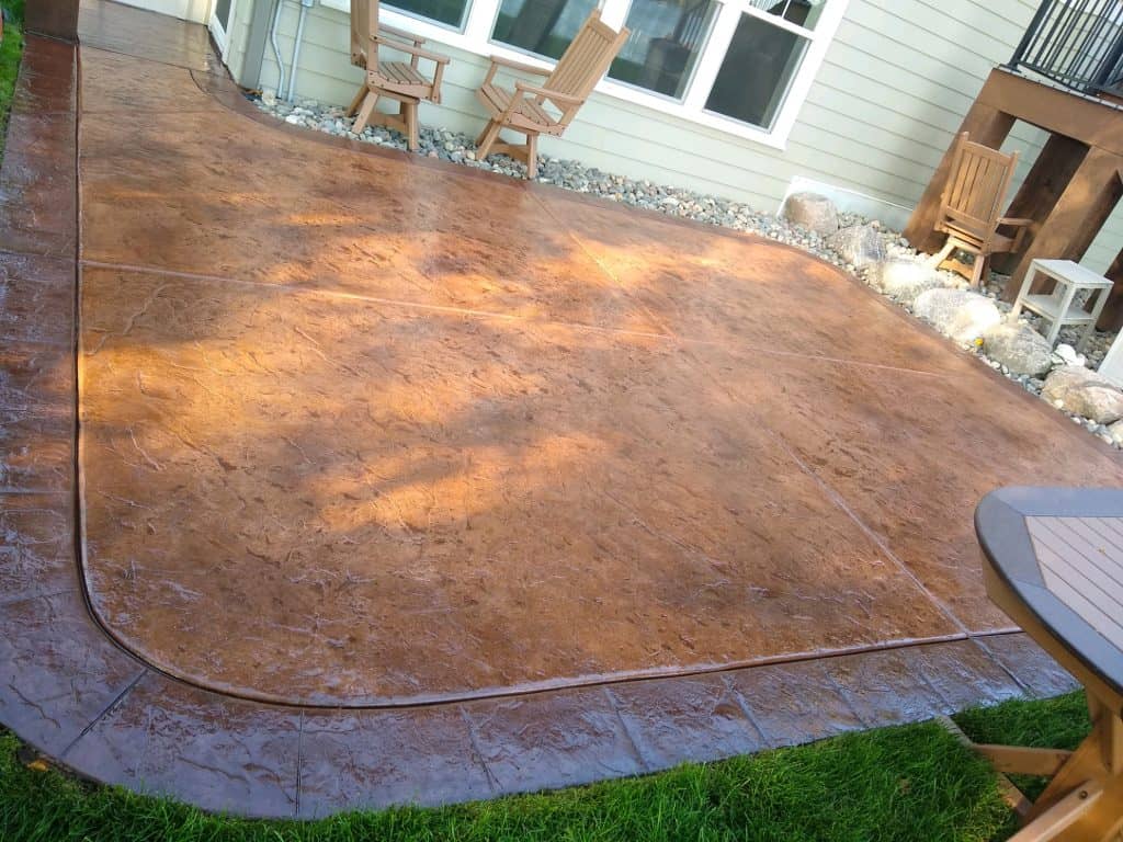 Decorative stamped concrete patio with curved edges and outdoor furniture.