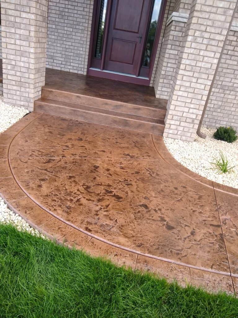A stunning stamped concrete front porch with curved design and textured finish, enhancing curb appea.