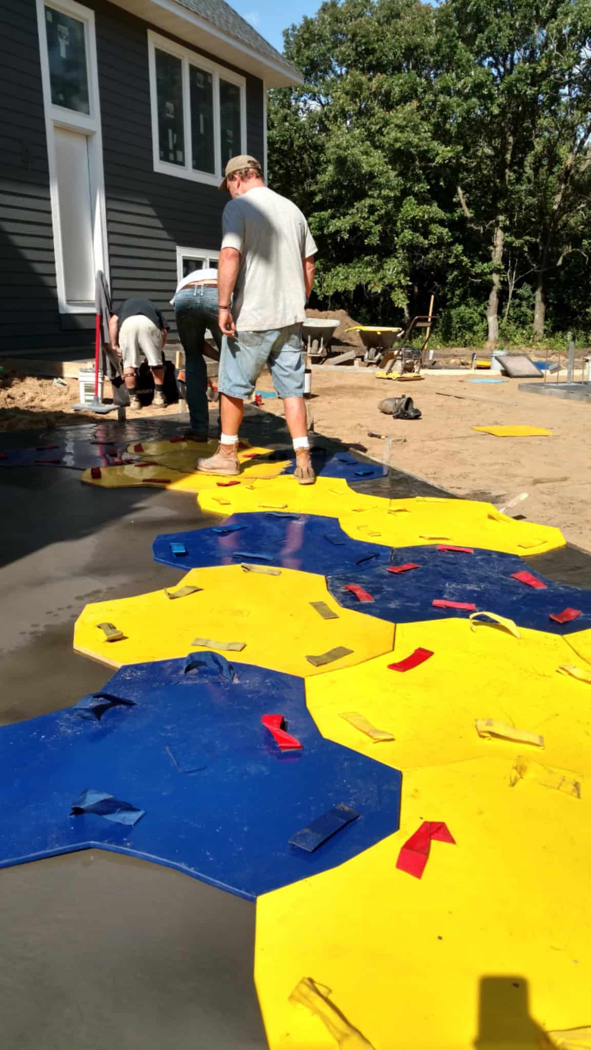Workers installing blue and yellow hexagonal outdoor tiles